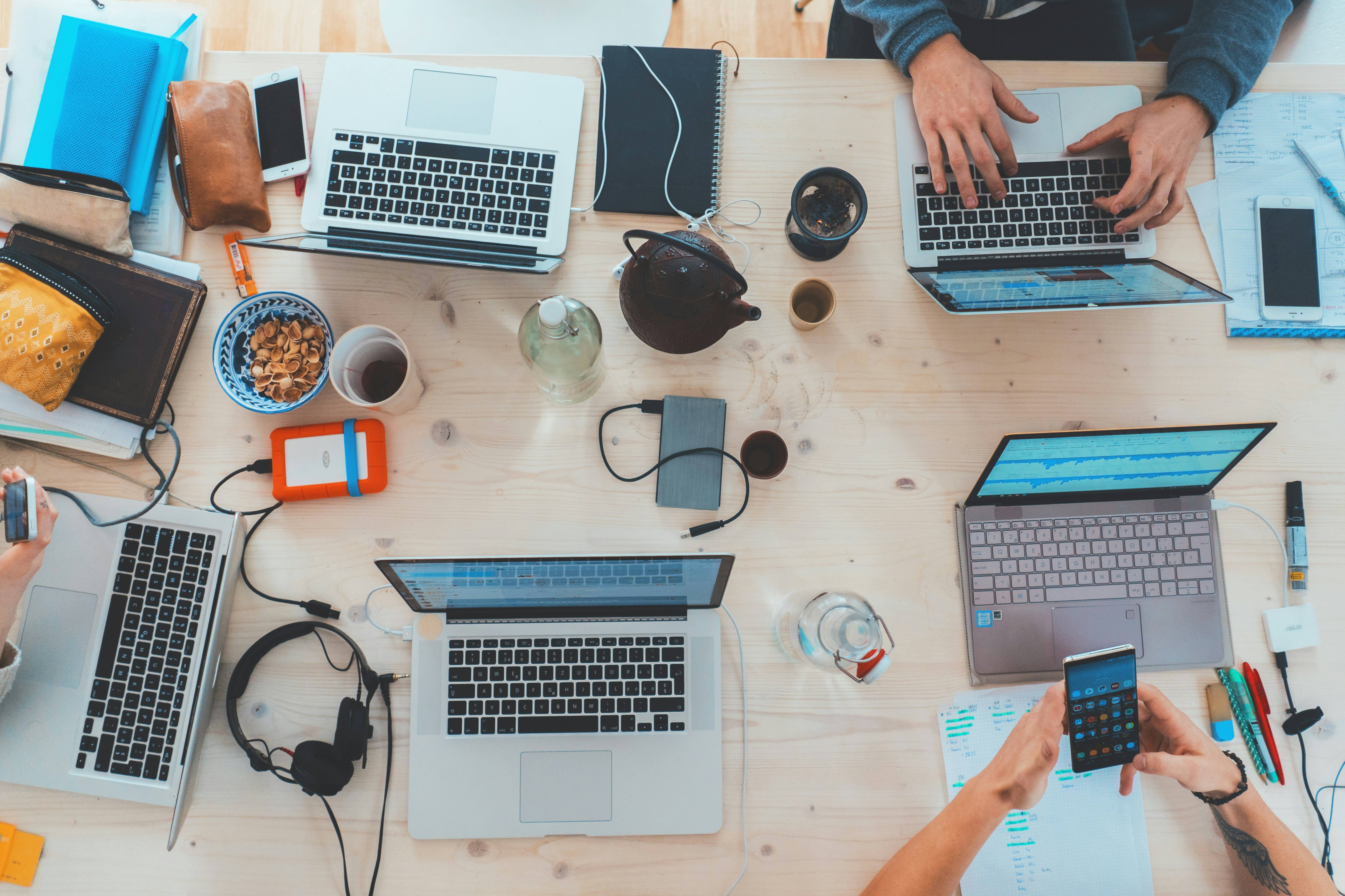 An overhead view of a cluttered desk with laptops and gadgets — a generic workspace stock photo, not an illustration of AI vendor pricing strategy