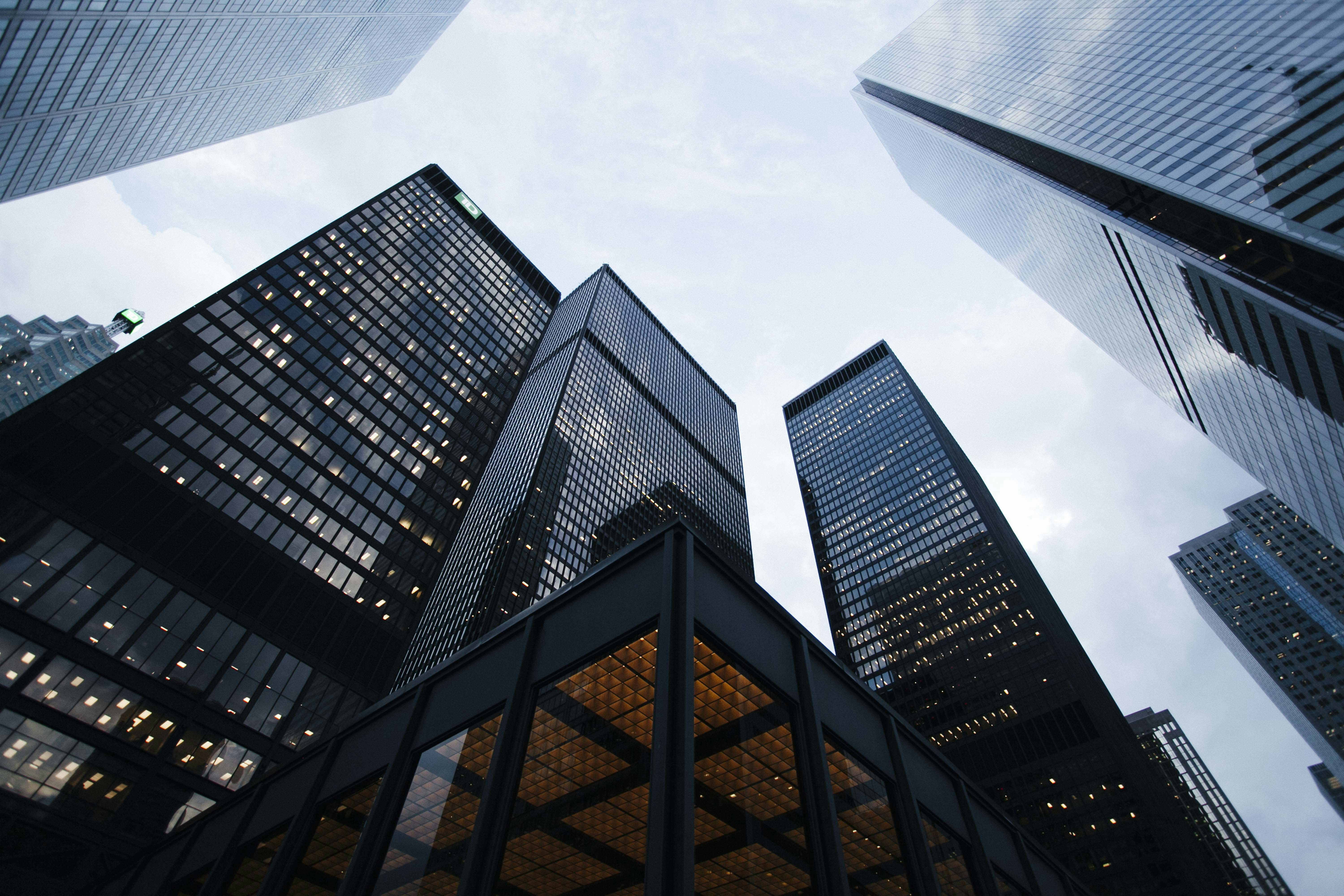 Office towers viewed from street level — a generic corporate stock photo, not an actual table comparing perceived and actual AI costs