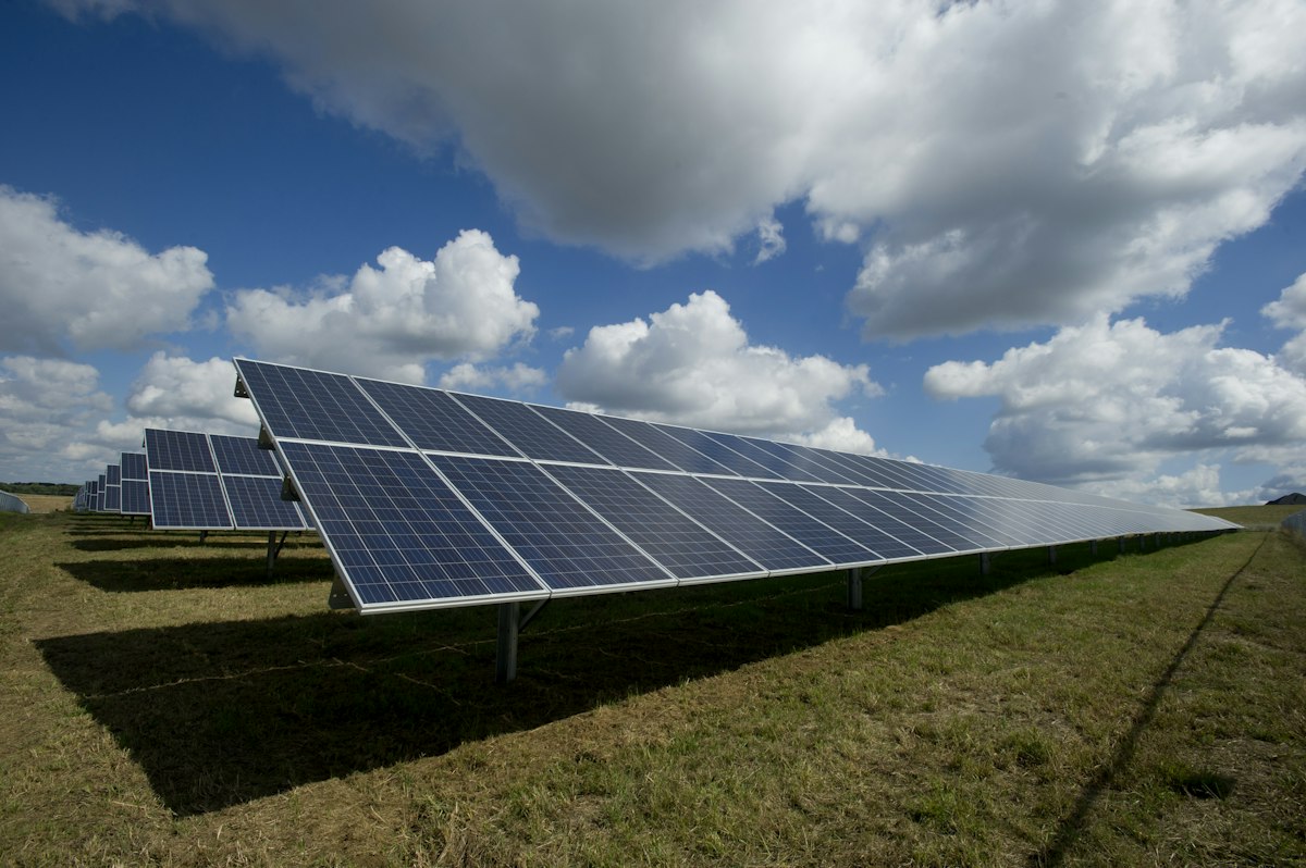 Rows of ground-based solar panels under a clear sky — generic stock photo illustrating the sunlight-power economics behind Google's orbital data center concept, not an actual depiction of the Project Suncatcher constellation or space-based solar arrays