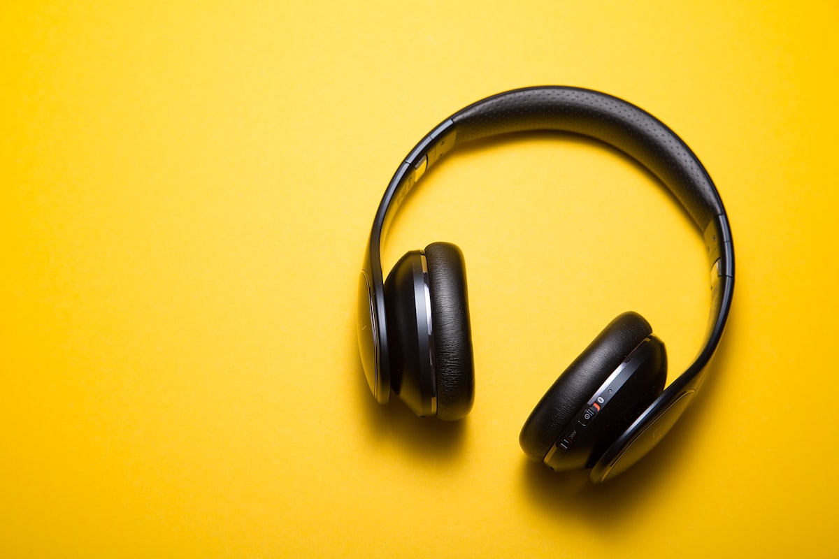 Generic over-ear headphones on a yellow background — a stock photo, not an actual product shot of smart earbuds or AR glasses