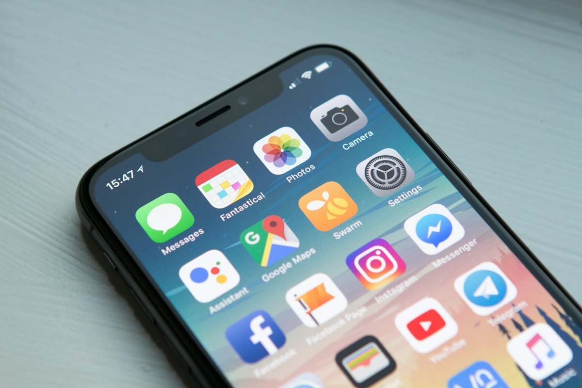 A smartphone leaning on a desk, home screen showing chat and social apps like Messages and Messenger — generic stock photo illustrating the consumer chatbot age-assurance debate, not an actual screenshot of ChatGPT